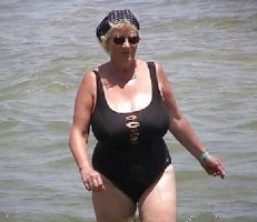 Blonde Slim and Busty Sexy Grandma in a Black Bathing Suit and Shades in Beach Water.jpg